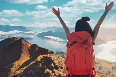 Asian woman hiker climbing up on the peak of mountain