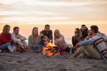 Friends sitting by the fire at the beach