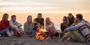 Friends sitting by the fire at the beach