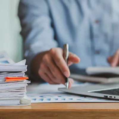Man grading papers with pen and computer - square