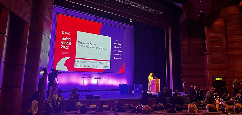 Speaker presenting on stage during an IELTS opening plenary session
