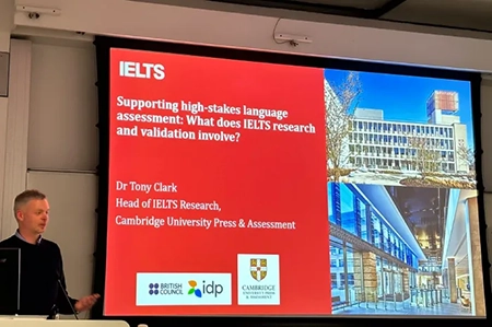 IELTS presentation by Dr Tony Clark on high stakes language assessment research shown on screen at UCL London
