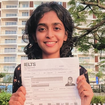 Student holding an IELTS test report form and smiling outdoors