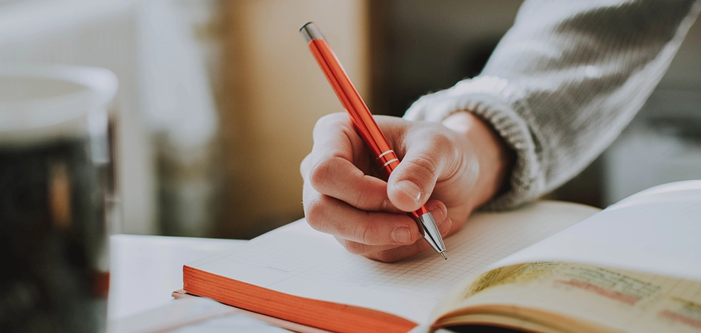 Close-up of hand writing in a notebook while studying