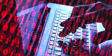 Hands typing on a laptop keyboard with red digital code overlay representing cybersecurity or online security