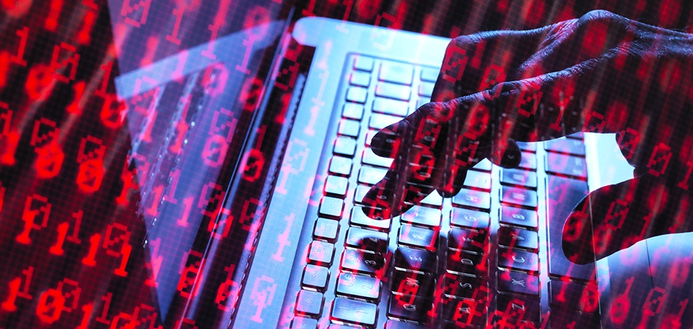 Hands typing on a laptop keyboard with red digital code overlay representing cybersecurity or online security