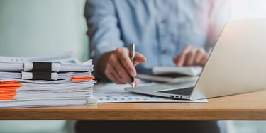 Man grading papers with pen and computer