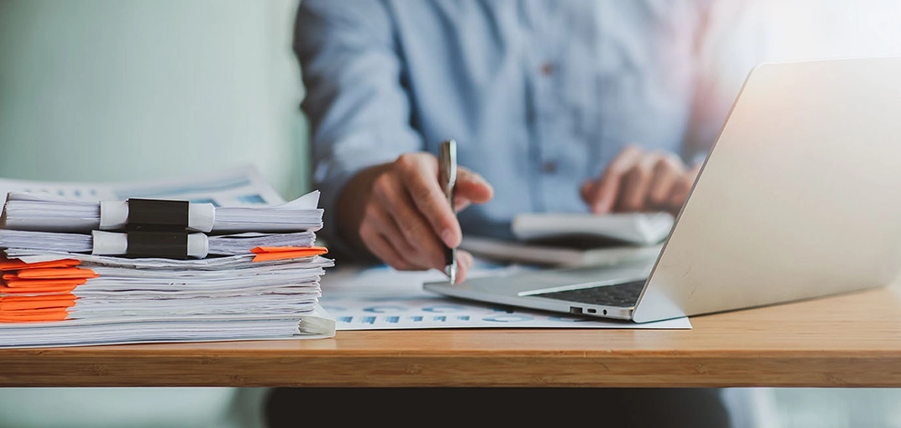 Man grading papers with pen and computer