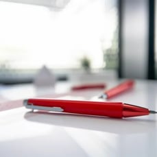 Red pen on a white desk with study notes in the background