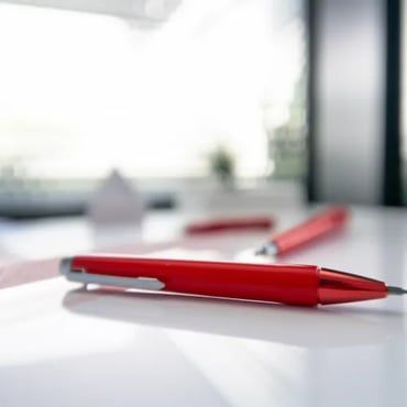 Red pen on a white desk with study notes in the background