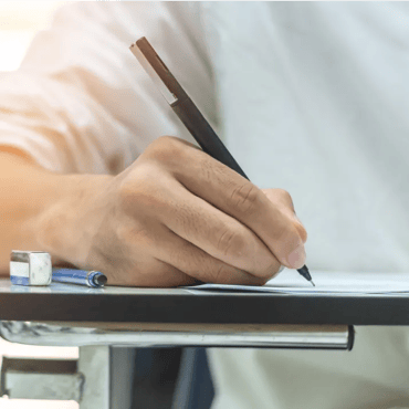 Close-up of hand writing answers on an IELTS test paper during an exam