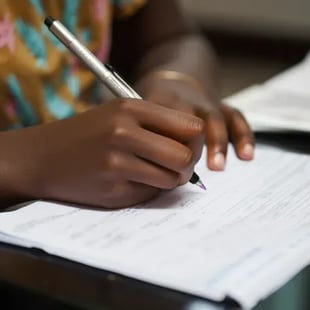 Hand writing answers on a paper answer sheet during an IELTS writing test