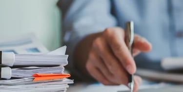 Man grading papers with pen and computer