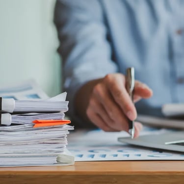 Man grading papers with pen and computer
