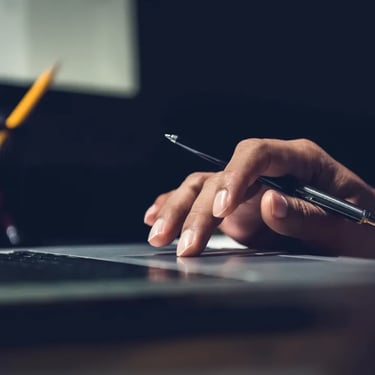 Person working on laptop with pen