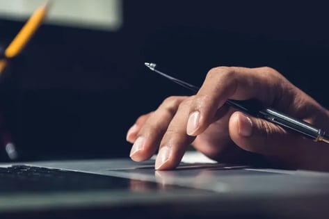 Person working on laptop with pen