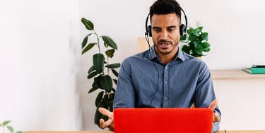 IELTS speaking practice online with a man wearing a headset talking to a laptop at a desk