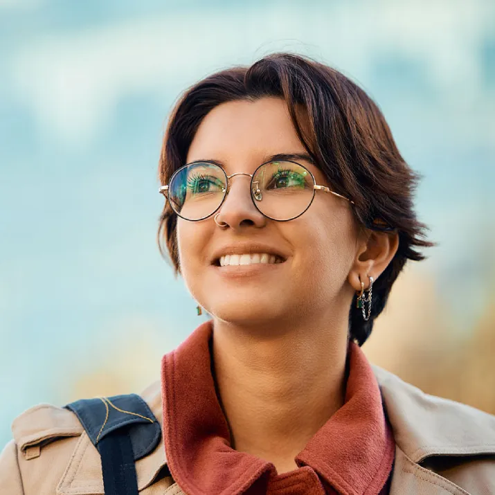 Young professional wearing glasses smiling outdoors representing IELTS career success