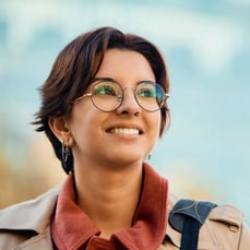 Young professional wearing glasses smiling outdoors representing IELTS career success