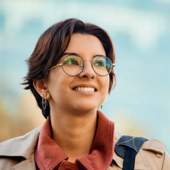 Young professional wearing glasses smiling outdoors representing IELTS career success