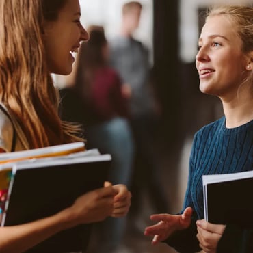 University students talking and holding study books in a campus hallway