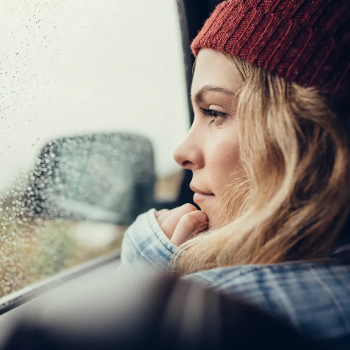 Woman wearing red hat looking out of car - left