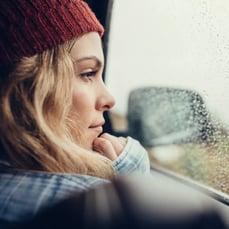 Woman wearing red hat looking out of car - right