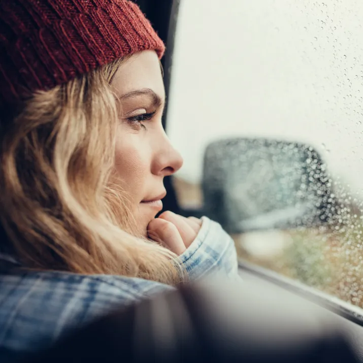 Woman wearing red hat looking out of car - right
