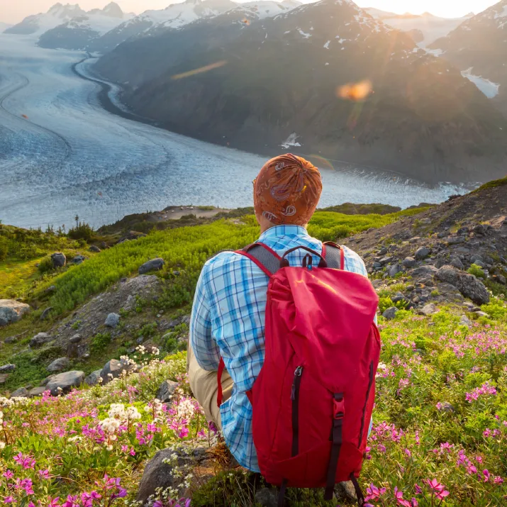 Man with red backpack looking down the valley