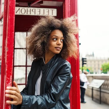 Woman stepping out of red telephone box