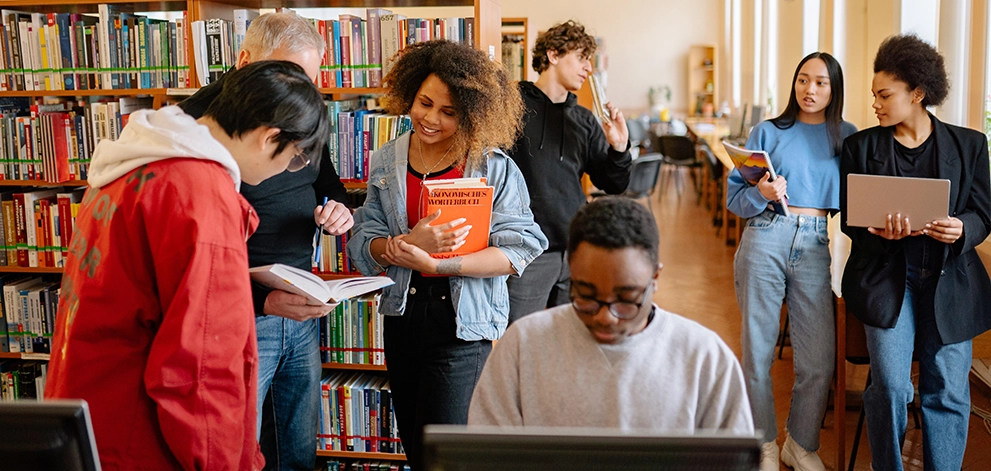 Group of students studying and reading books together in a library
