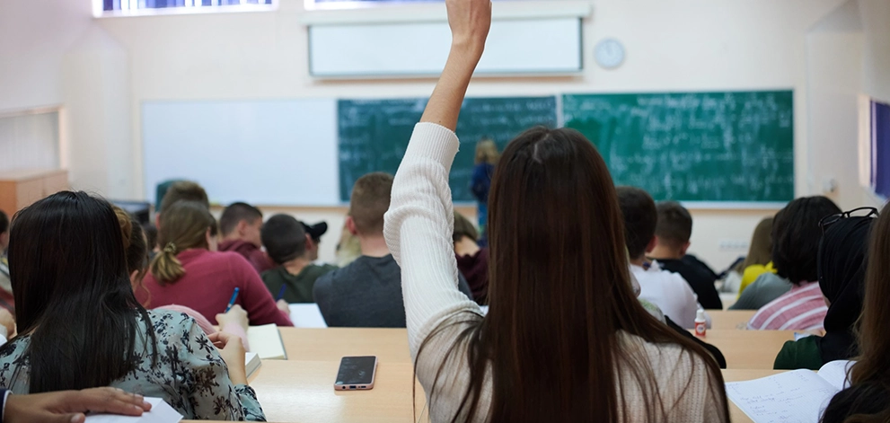 Student raising hand in lecture hall
