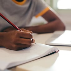 Student writing notes during a classroom lecture while preparing for IELTS