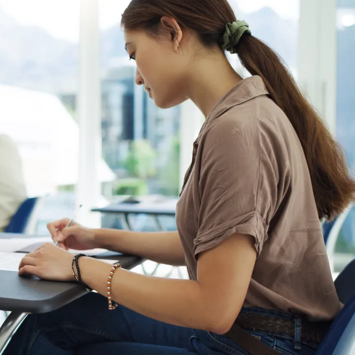 Student writing answers during an IELTS exam in a classroom