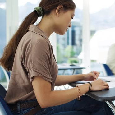 Student writing answers during an IELTS exam in a classroom