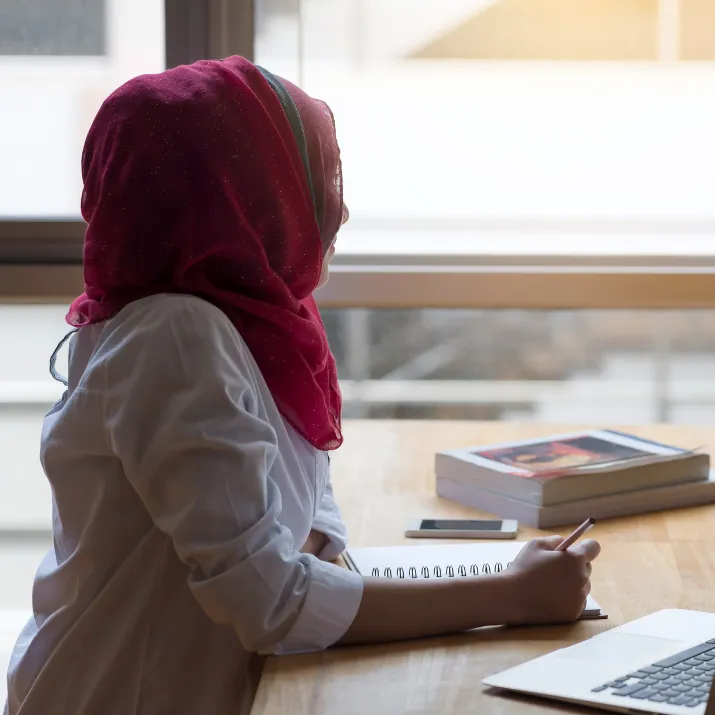 Student in headscarf looking out window