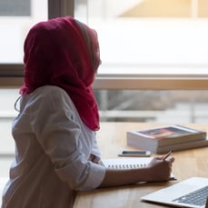 Student in headscarf looking out window