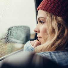 Woman in red hat looking out rainy car window