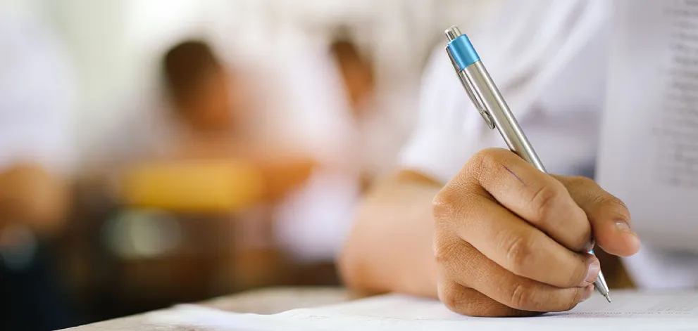 Close-up of a hand writing on an exam paper in a test setting
