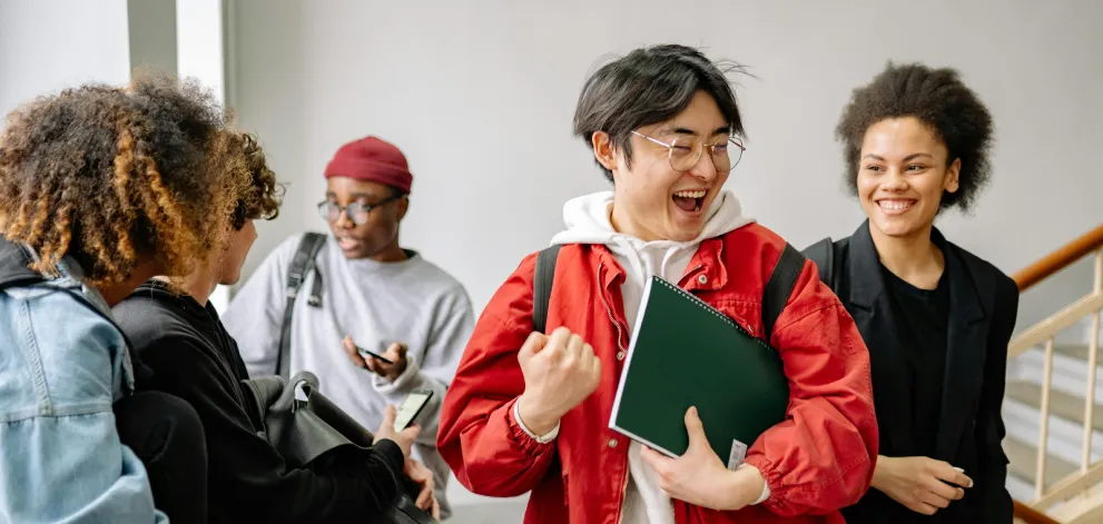 Group of students in a hallway engaged in conversation and celebration