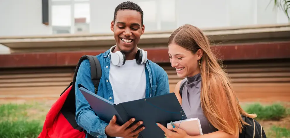 Male and female students reviewing notes outdoors in an academic setting